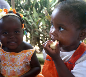 Two young Haitian girls eating bread