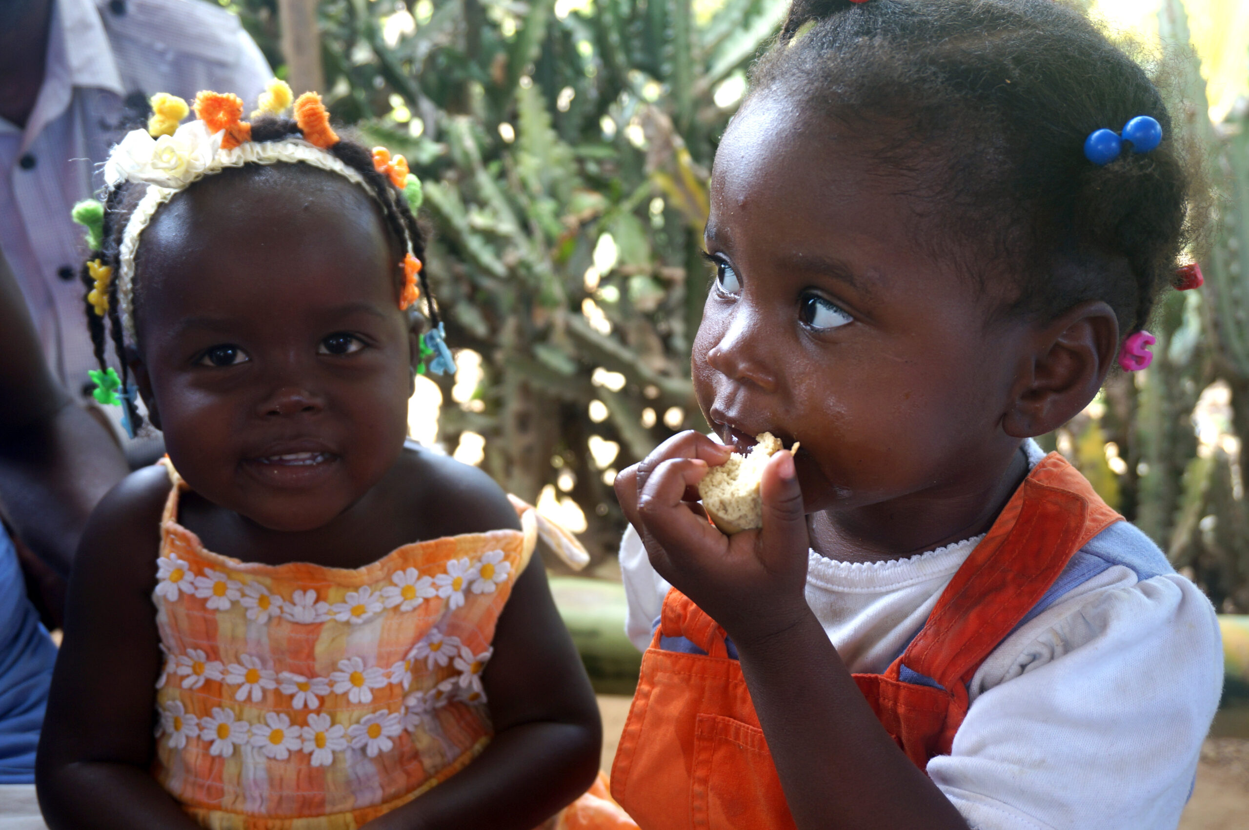 Two young Haitian girls eating bread