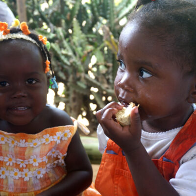 Two young Haitian girls eating bread